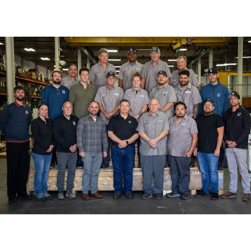 The Bonnot Company team of 21 people standing in three rows on the shop floor of Bonnot’s extruder manufacturing facility in Akron, Ohio.